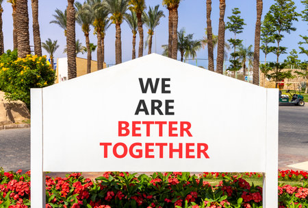We are better together symbol. Concept words phrase We are better together on beautiful white road sign. Beautiful palm tree blue sky background. Business We are better together concept. Copy space.の写真素材