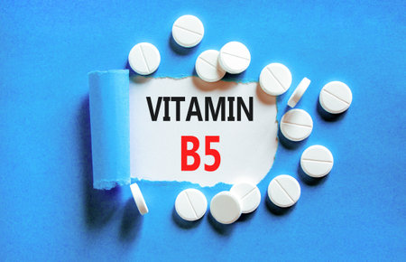 Vitamin B5 pantothenic acid symbol. Concept words Vitamin B5 on beautiful white paper. White pills tablets. Beautiful blue background. Medical healthy lifestyle Vitamin B5 concept.の写真素材