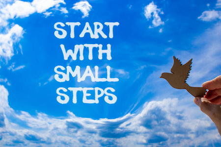 Start with small steps symbol. Concept words phrase Start with small steps on beautiful blue sky. Businessman's hand. Beautiful blue sky background. Business Start with small steps concept. Copy spaceの写真素材