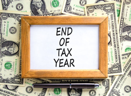 End of tax year symbol. Concept words phrase End of tax year on beautiful wooden picture frame. Dollar bills. Beautiful dollar bills background. Business End of tax year concept. Copy space.の写真素材