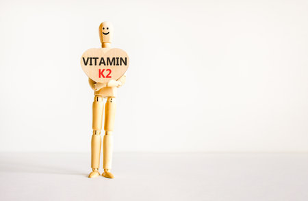 Vitamin K2 phylloquinone symbol. Concept words Vitamin K2 on beautiful wooden heart. Doctor's model. Beautiful white background. Copy space. Medical healthy lifestyle Vitamin K2 phylloquinone concept.の写真素材