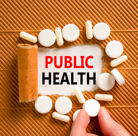 Public health symbol. Concept words Public health on beautiful white paper. White pills tablets. Doctor's hand. Beautiful brown background. Medical healthy lifestyle public health concept.の写真素材