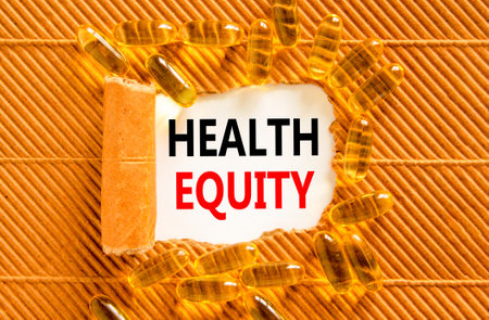 Health equity symbol. Concept words Health equity on beautiful white paper. Yellow pills tablets. Beautiful brown background. Medical healthy lifestyle health equity concept.の写真素材