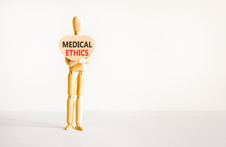 Medical ethics symbol. Concept words Medical ethics on beautiful wooden heart. Doctor's model. Beautiful white background. Copy space. Medical healthy lifestyle medical ethics concept.の写真素材