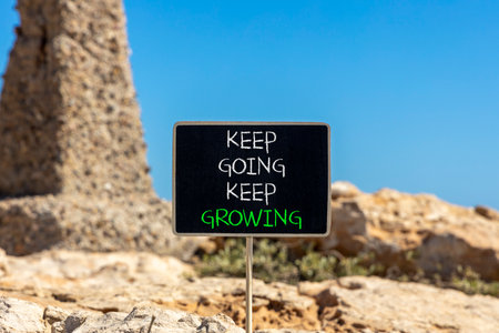 Keep going and growing symbol. Concept words phrase Keep going keep growing on beautiful black blackboard. Beautiful stone blue sky background. Business Keep going and growing concept. Copy space.の写真素材