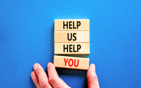 Help you symbol. Concept words phrase Help us help you on beautiful wooden blocks. Beautiful blue paper background. Businessman's hand. Business Help you concept. Copy space.の写真素材