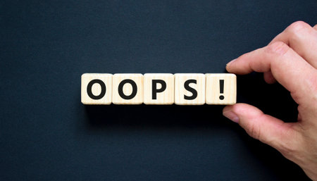 Oops symbol. Concept word Oops on beautiful wooden blocks. Beautiful black table black background. Businessman hand. Business lifestyle oops concept. Copy space.の写真素材