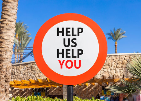 Help you symbol. Concept words phrase Help us help you on beautiful road sign. Beautiful palm tree and blue sky background. Business Help you concept. Copy space.の写真素材