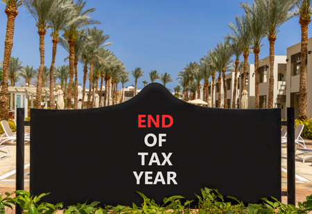 End of tax year symbol. Concept words phrase End of tax year on beautiful big black road sign. Beautiful palm tree blue sky background. Business End of tax year concept. Copy space.の写真素材