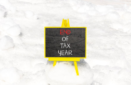 End of tax year symbol. Concept words phrase End of tax year on beautiful black blackboard. Beautiful white snow background. Business End of tax year concept. Copy space.の写真素材