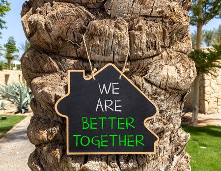 We are better together symbol. Concept words phrase We are better together on beautiful black blackboard. Beautiful old palm tree background. Business We are better together concept. Copy space.の写真素材