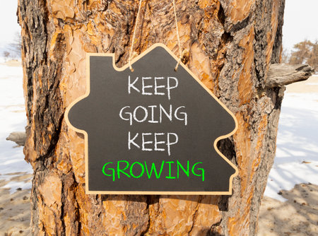 Keep going and growing symbol. Concept words phrase Keep going keep growing on beautiful black blackboard. Beautiful old pine tree background. Business Keep going and growing concept. Copy space.の写真素材