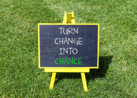 Turn change into chance symbol. Concept words phrase Turn change into chance on beautiful black blackboard. Beautiful green grass lawn background. Business Turn change into chance concept. Copy space.の写真素材