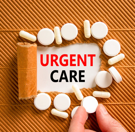 Urgent care symbol. Concept words Urgent care on beautiful white paper. White pills tablets. Doctor's hand. Beautiful brown background. Medical healthy lifestyle urgent care concept.の写真素材
