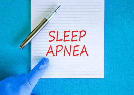 Sleep apnea symbol. Concept words Sleep apnea on beautiful white note. Doctor's hand in blue medical glove. Black pen. Beautiful blue background. Medical healthy lifestyle sleep apnea concept.の写真素材