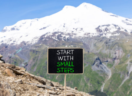 Start with small steps symbol. Concept words phrase Start with small steps on beautiful black blackboard. Beautiful mountain Elbrus background. Business Start with small steps concept. Copy space.の写真素材