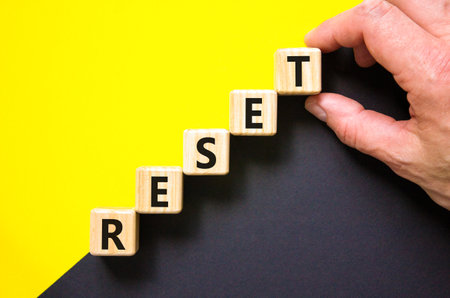 Reset symbol. Concept word Reset on beautiful wooden blocks. Beautiful yellow and black background. Businessman hand. Business lifestyle reset concept. Copy space.の写真素材