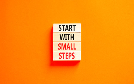 Start with small steps symbol. Concept words phrase Start with small steps on beautiful wooden blocks. Beautiful orange paper background. Business Start with small steps concept. Copy space.の写真素材