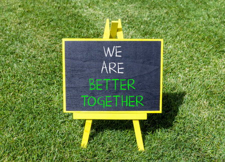 We are better together symbol. Concept words phrase We are better together on beautiful black blackboard. Beautiful green grass lawn background. Business We are better together concept. Copy space.の写真素材