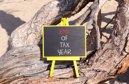 End of tax year symbol. Concept words phrase End of tax year on beautiful black blackboard. Beautiful old tree background. Business End of tax year concept. Copy space.の写真素材