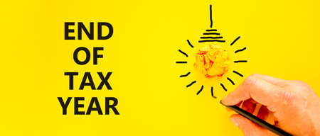 End of tax year symbol. Concept words phrase End of tax year on beautiful yellow paper. Businessman's hand. Beautiful yellow paper background. Business End of tax year concept. Copy space.の写真素材