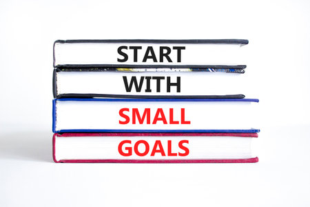 Start with small goals symbol. Concept words phrase Start with small goals on beautiful books. Beautiful white paper background. Business Start with small goals concept. Copy space.の写真素材
