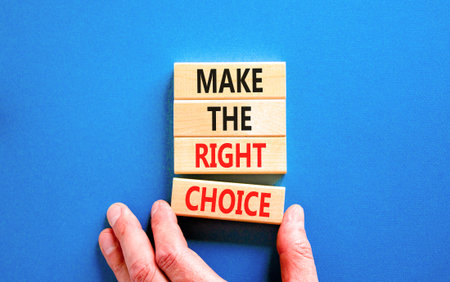 Make the right choice symbol. Concept words phrase Make the right choice on beautiful wooden blocks. Beautiful blue background. Businessman's hand. Business Make the right choice concept. Copy space.の写真素材