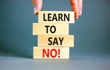 Learn to say no symbol. Concept words phrase Learn to say no on beautiful wooden blocks. Beautiful gray paper background. Businessman's hand. Business psychological Learn to say no concept. Copy spaceの写真素材