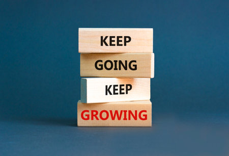 Keep going and growing symbol. Concept words phrase Keep going keep growing on beautiful wooden blocks. Beautiful gray paper background. Business Keep going and growing concept. Copy space.の写真素材