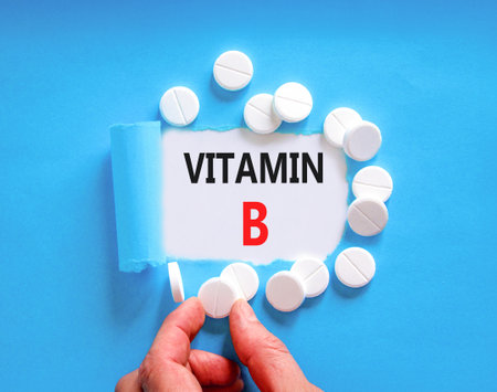 Vitamin B symbol. Concept words Vitamin B on beautiful white paper. White pills tablets. Doctor's hand. Beautiful blue background. Medical healthy lifestyle Vitamin B concept.の写真素材