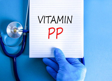 Vitamin PP symbol. Concept words Vitamin PP on beautiful white note. Doctor's hand in blue medical glove. Stethoscope. Beautiful blue background. Medical healthy lifestyle Vitamin PP concept.の写真素材
