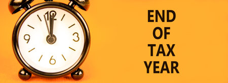 End of tax year symbol. Concept words phrase End of tax year on beautiful orange paper. Black alarm clock. Beautiful orange paper background. Business End of tax year concept. Copy space.の写真素材