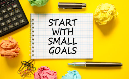 Start with small goals symbol. Concept words phrase Start with small goals on beautiful white note. Colored paper. Beautiful yellow background. Business Start with small goals concept. Copy spaceの写真素材