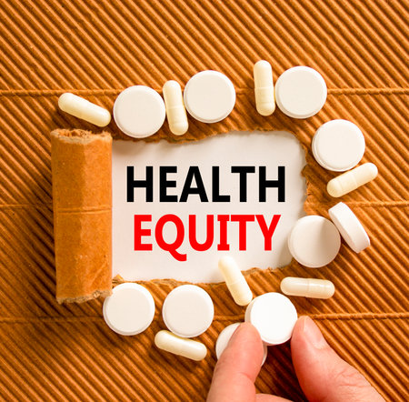 Health equity symbol. Concept words Health equity on beautiful white paper. White pills tablets. Doctor's hand. Beautiful brown background. Medical healthy lifestyle health equity concept.の写真素材