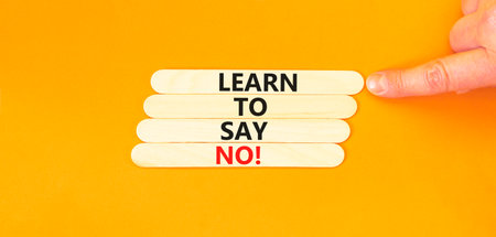 Learn to say no symbol. Concept words phrase Learn to say no on beautiful wooden stick. Businessman's hand. Beautiful orange background. Business psychological Learn to say no concept. Copy space.の写真素材