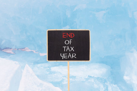 End of tax year symbol. Concept words phrase End of tax year on beautiful black blackboard. Beautiful blue ice background. Business End of tax year concept. Copy space.の写真素材