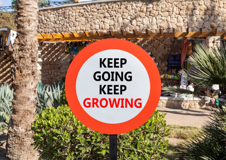 Keep going and growing symbol. Concept words phrase Keep going keep growing on beautiful road sign. Beautiful palm tree background. Business Keep going and growing concept. Copy space.の写真素材