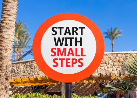 Start with small steps symbol. Concept words phrase Start with small steps on beautiful road sign. Beautiful palm tree and blue sky background. Business Start with small steps concept. Copy space.の写真素材