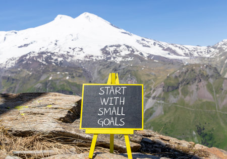 Start with small goals symbol. Concept words phrase Start with small goals on beautiful black blackboard. Beautiful mountain Elbrus background. Business Start with small goals concept. Copy space.の写真素材