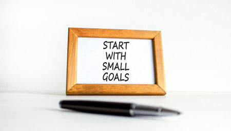 Start with small goals symbol. Concept words phrase Start with small goals on beautiful wooden picture frame. Black pen. Beautiful white background. Business Start with small goals concept. Copy spaceの写真素材