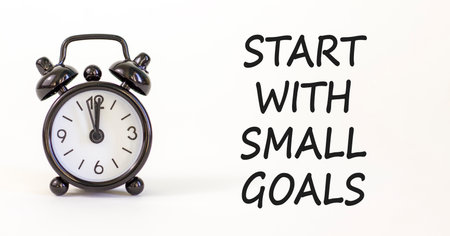 Start with small goals symbol. Concept words phrase Start with small goals on beautiful white paper. Black alarm clock. Beautiful white background. Business Start with small goals concept. Copy space.の写真素材