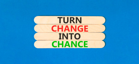 Turn change into chance symbol. Concept words phrase Turn change into chance on beautiful wooden stick. Beautiful blue paper background. Business Turn change into chance concept. Copy space.の写真素材