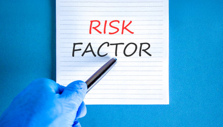 Risk factor symbol. Concept words Risk factor on beautiful white note. Doctor's hand in blue medical...