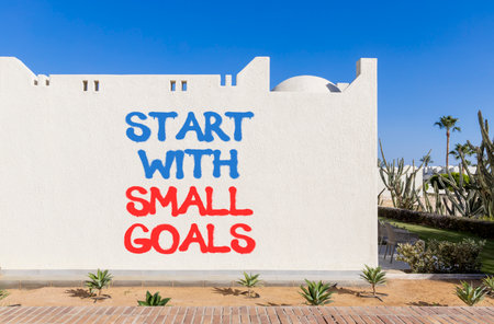 Start with small goals symbol. Concept words phrase Start with small goals on beautiful white wall. Beautiful white wall and blue sky background. Business Start with small goals concept. Copy space.の写真素材