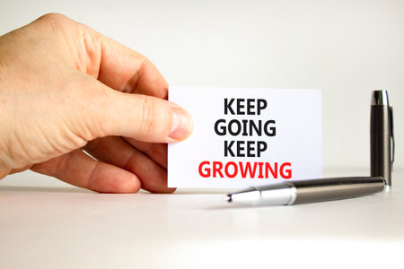 Keep going and growing symbol. Concept words phrase Keep going keep growing on beautiful white card. Businessman's hand. Beautiful white paper background. Business Keep going and growing concept. Copy spaceの写真素材