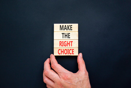 Make the right choice symbol. Concept words phrase Make the right choice on beautiful wooden blocks. Beautiful black background. Businessman's hand. Business Make the right choice concept. Copy space.の写真素材
