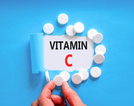 Vitamin C symbol. Concept words Vitamin C on beautiful white paper. White pills tablets. Doctor's hand. Beautiful blue background. Medical healthy lifestyle Vitamin C concept.の写真素材