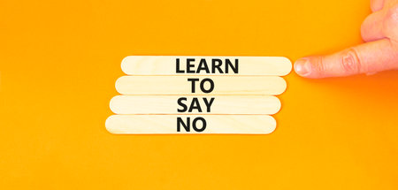 Learn to say no symbol. Concept words phrase Learn to say no on beautiful wooden stick. Businessman's hand. Beautiful orange background. Business psychological Learn to say no concept. Copy space.の写真素材