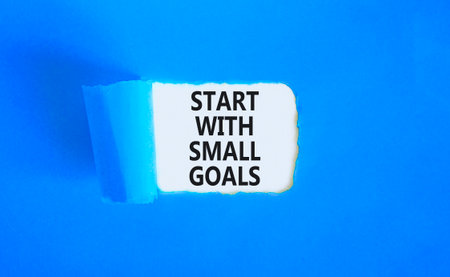 Start with small goals symbol. Concept words phrase Start with small goals on beautiful white paper. Beautiful blue paper background. Business Start with small goals concept. Copy space.の写真素材