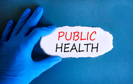 Public health symbol. Concept words Public health on beautiful white paper. Doctor's hand in blue medical glove. Beautiful blue background. Medical healthy lifestyle public health concept.の写真素材
